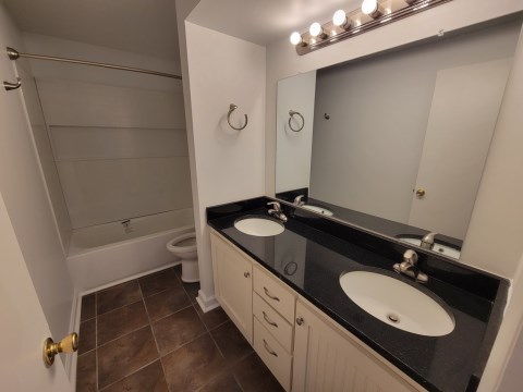 Renovated bathroom with double vanity w/ granite countertops and new bathtub and surround