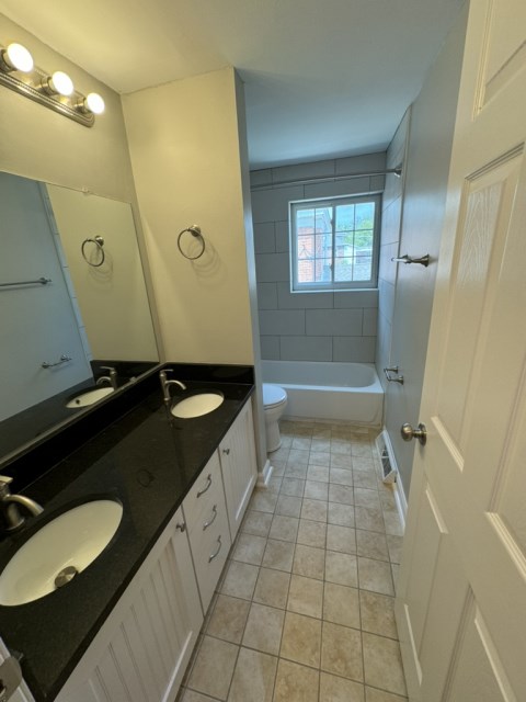 Renovated bathroom w/ new bathtub, surround and double vanity with granite countertops