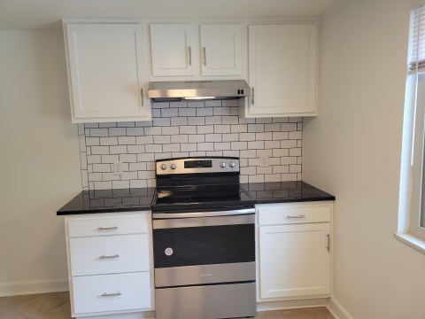 Range w/ cabinets on each side & white subway tile