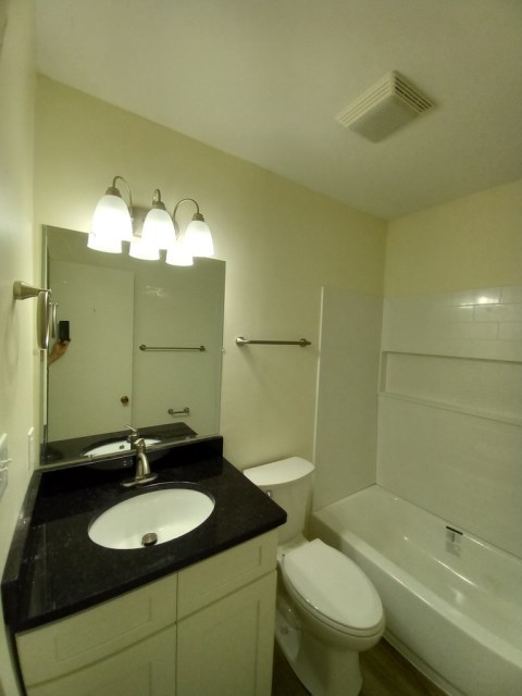 Renovated bathroom with new bathtub and surround and new vanity with granite countertops
