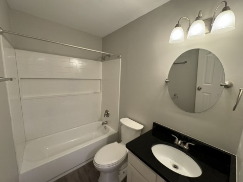 Renovated bathroom with new bathtub and surround and new vanity with granite countertops