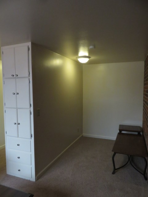 Bed area and storage cabinets with the entryway on the left.